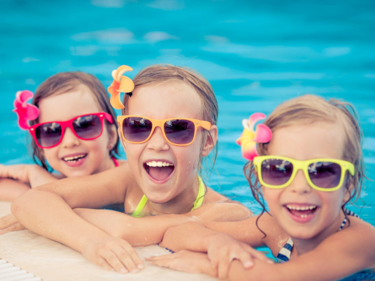 Three girls with sunglasses in the pool smiling